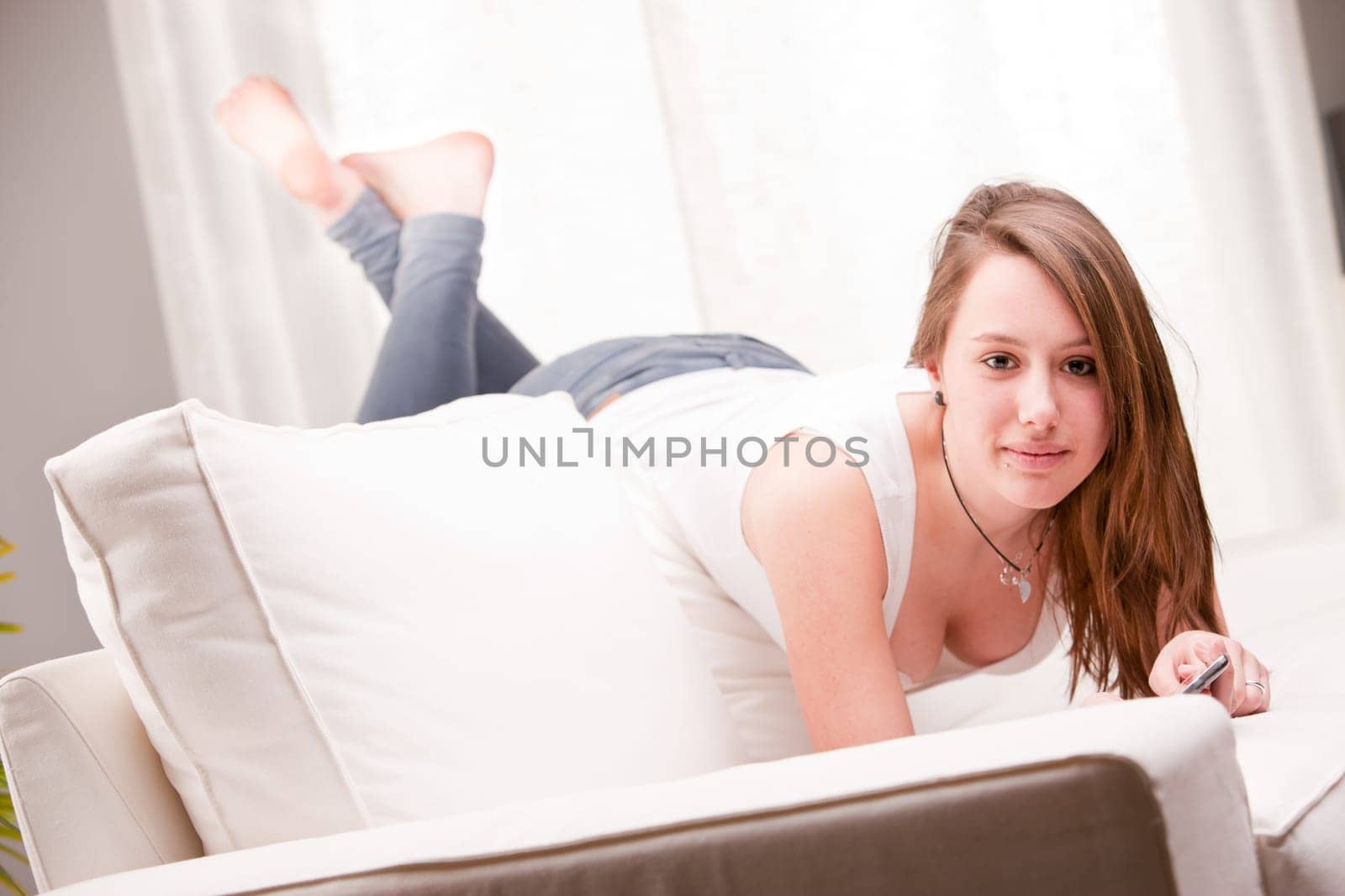 smiling girl in a strange position on a couch staring at you