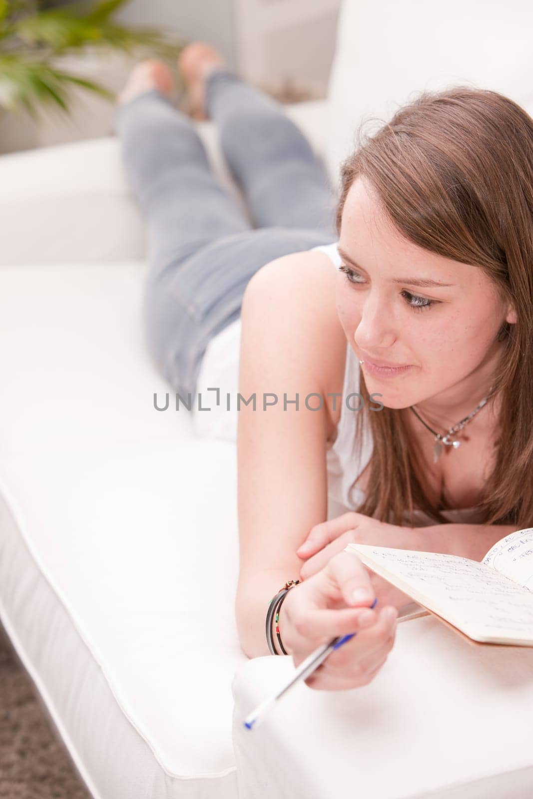 girl reading and studying while lying on her sofa in her living room