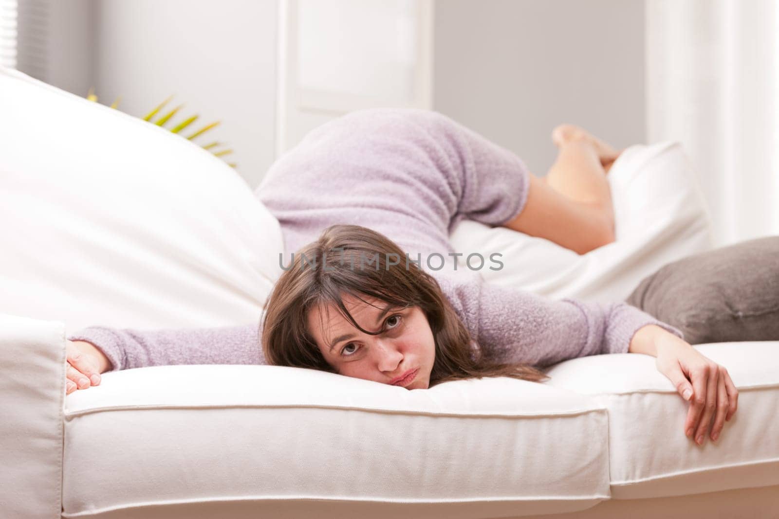 funny girl showing fatigue throwing herself on the sofa in her living room after a long day at work