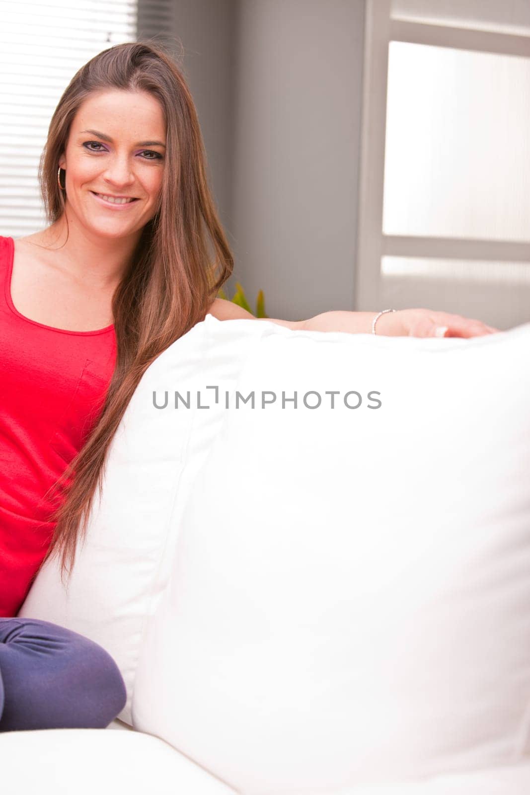 young sexy woman smiling on a couch in her living room happy and relaxed because she's successful