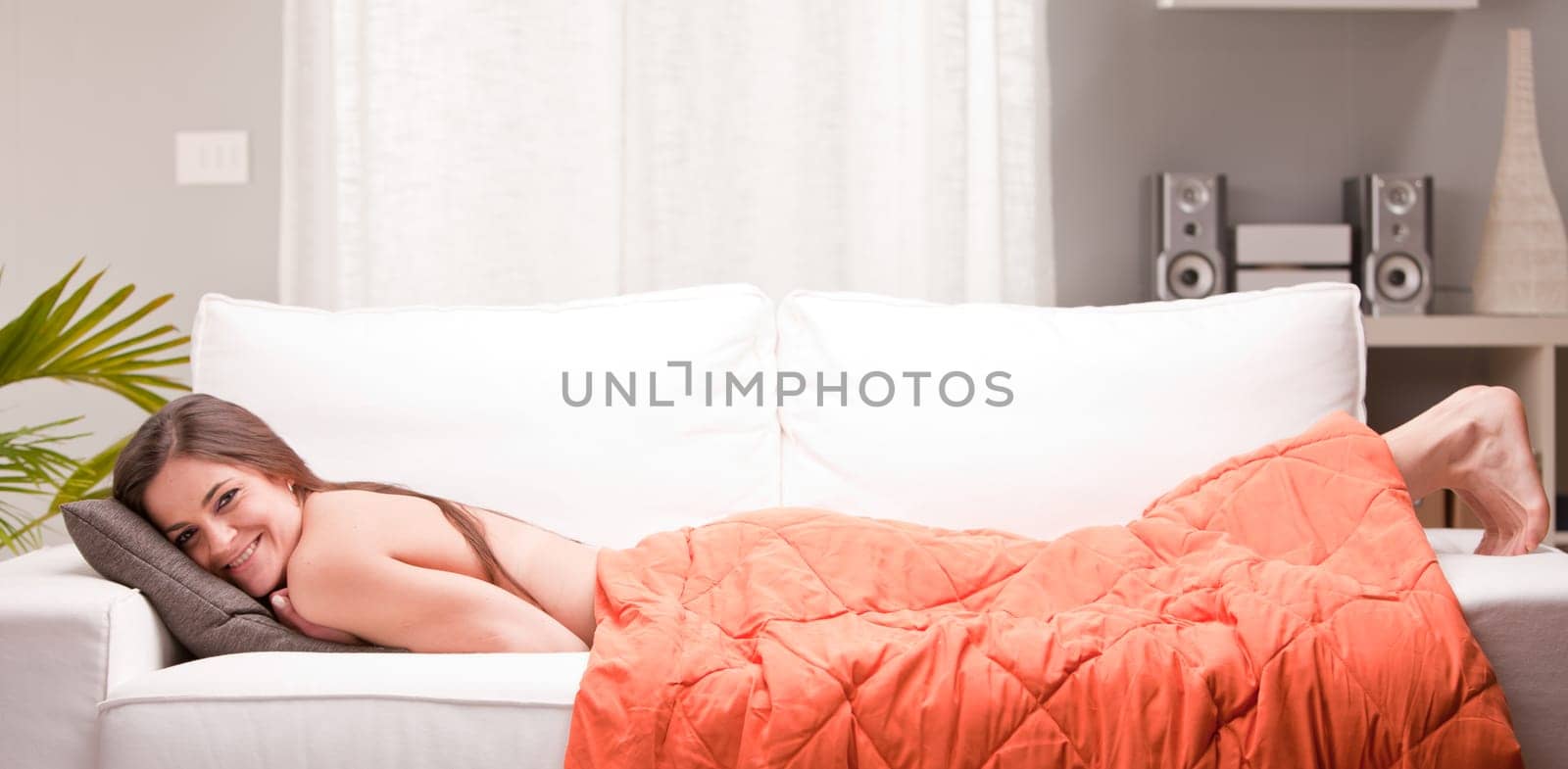 young sexy woman smiling on a couch in her living room happy and relaxed because she's successful