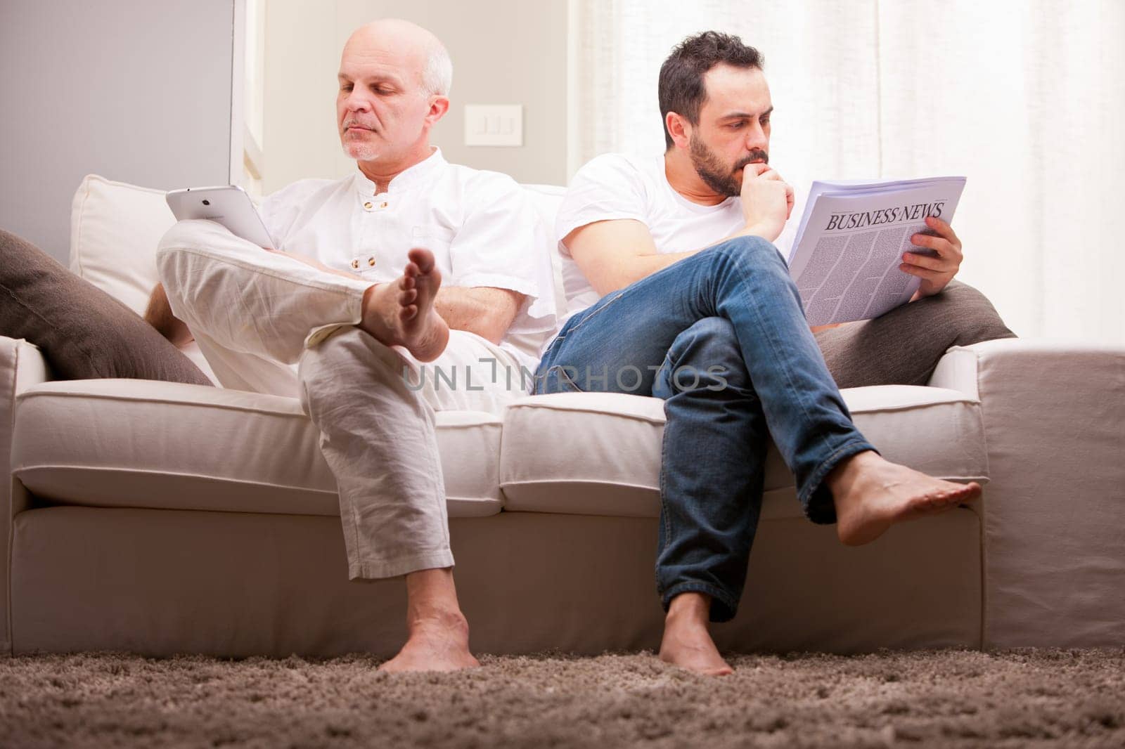 men reading on a sofa in a white living room in relax