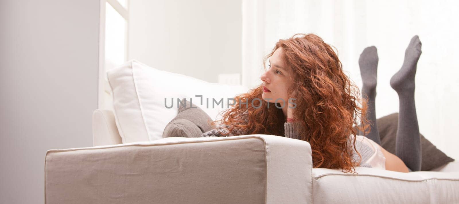 Red Headed very cute girl thinking seriously on her sofa in her living room