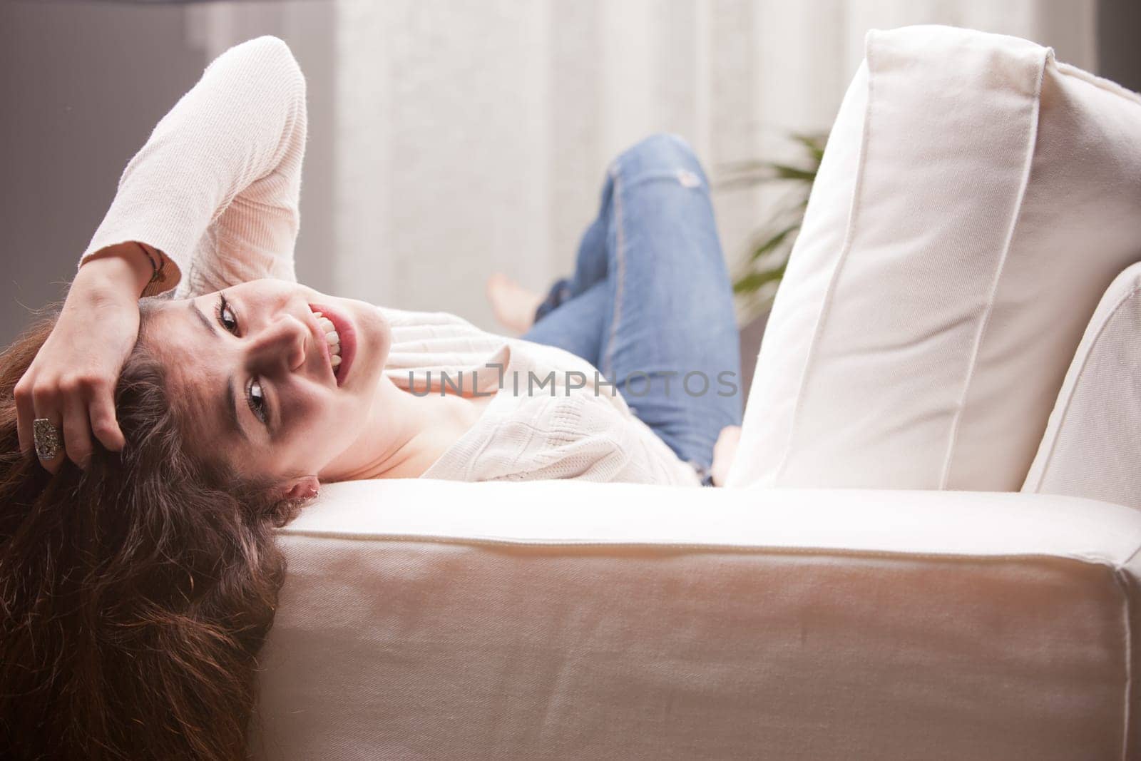young pretty girl lying on a couch and smiling on her living room because her life is good
