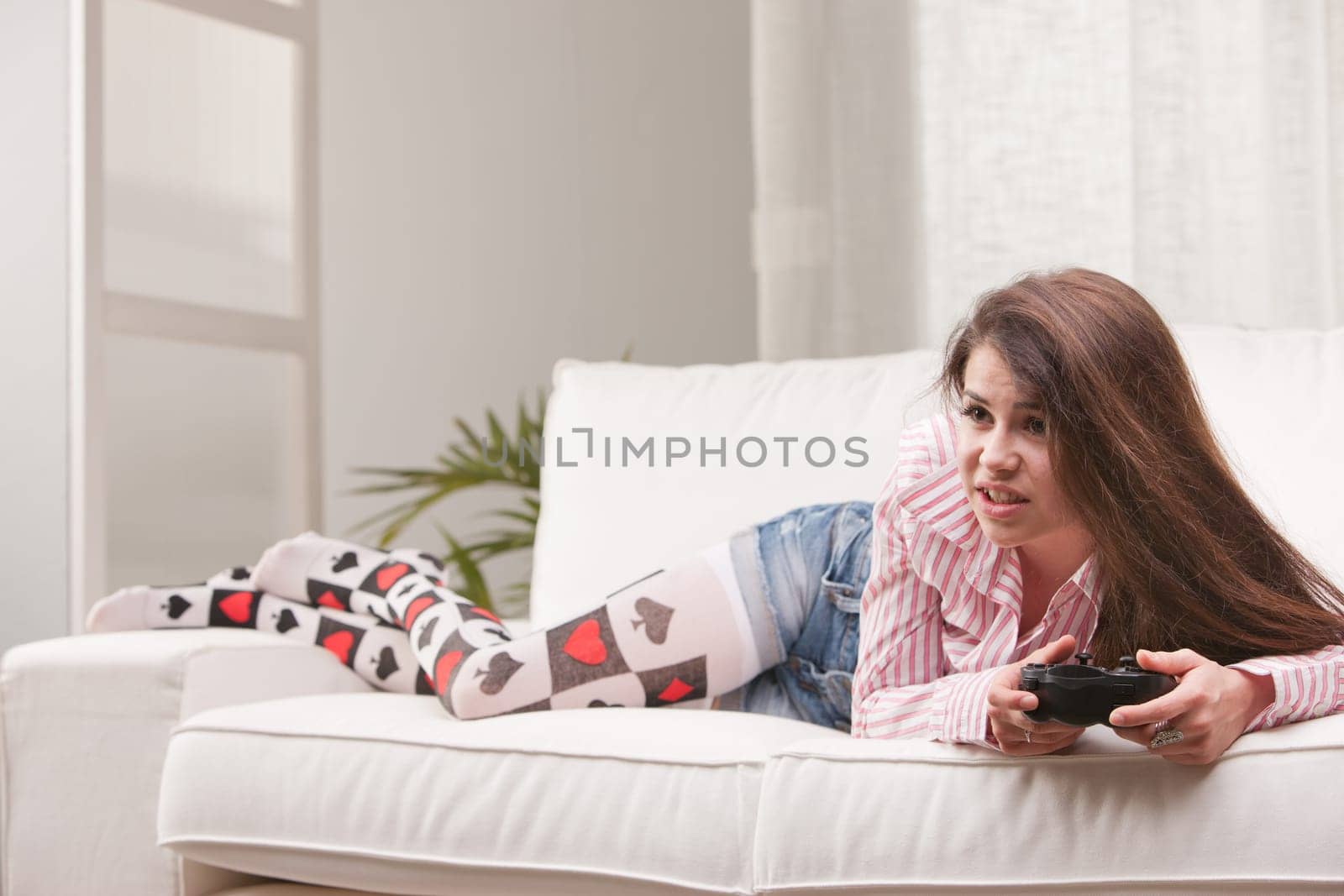pretty girl absorbed playing videogames at home on her sofa in her living room