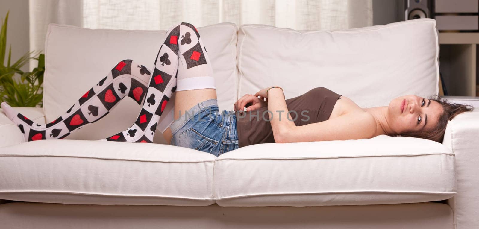 smiling girl lying on her couch in her living room watching to the camera