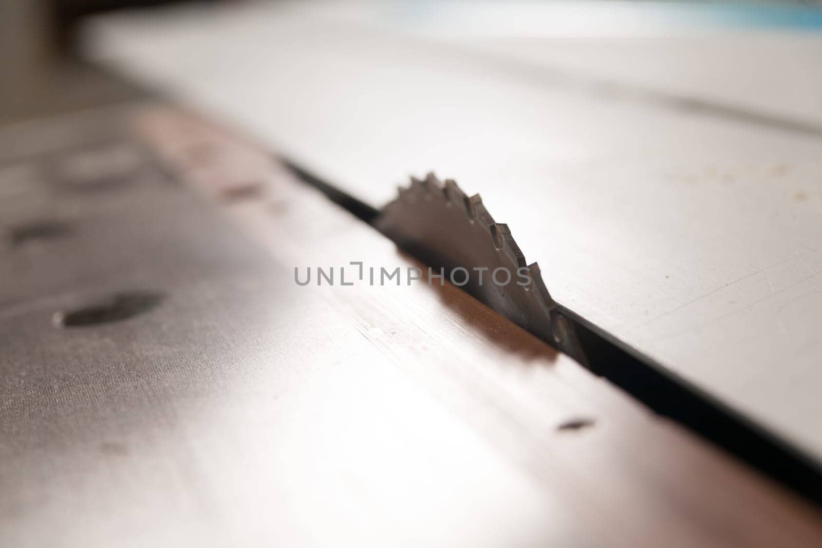 detail of the blade of a circular saw in a carpenter workshop with a very shallow depth of field