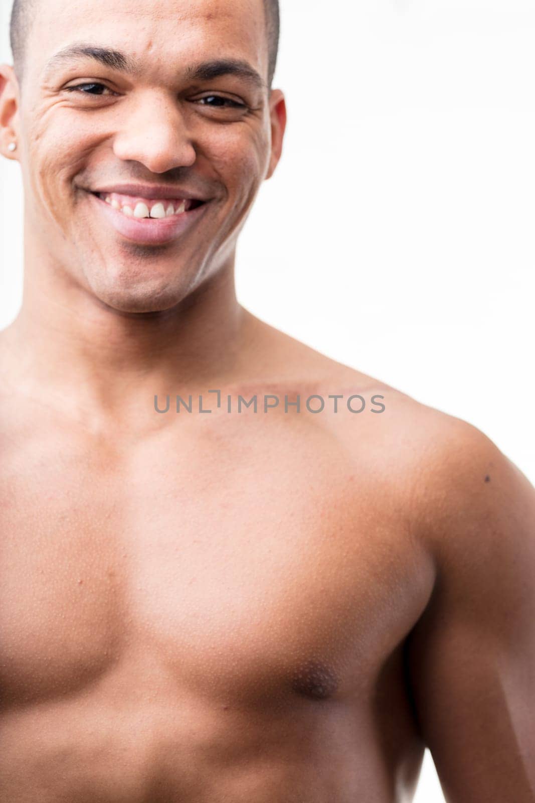 smiling afro-american man portrait, his chest is naked and showing pectoral muscles as well as a strong biceps