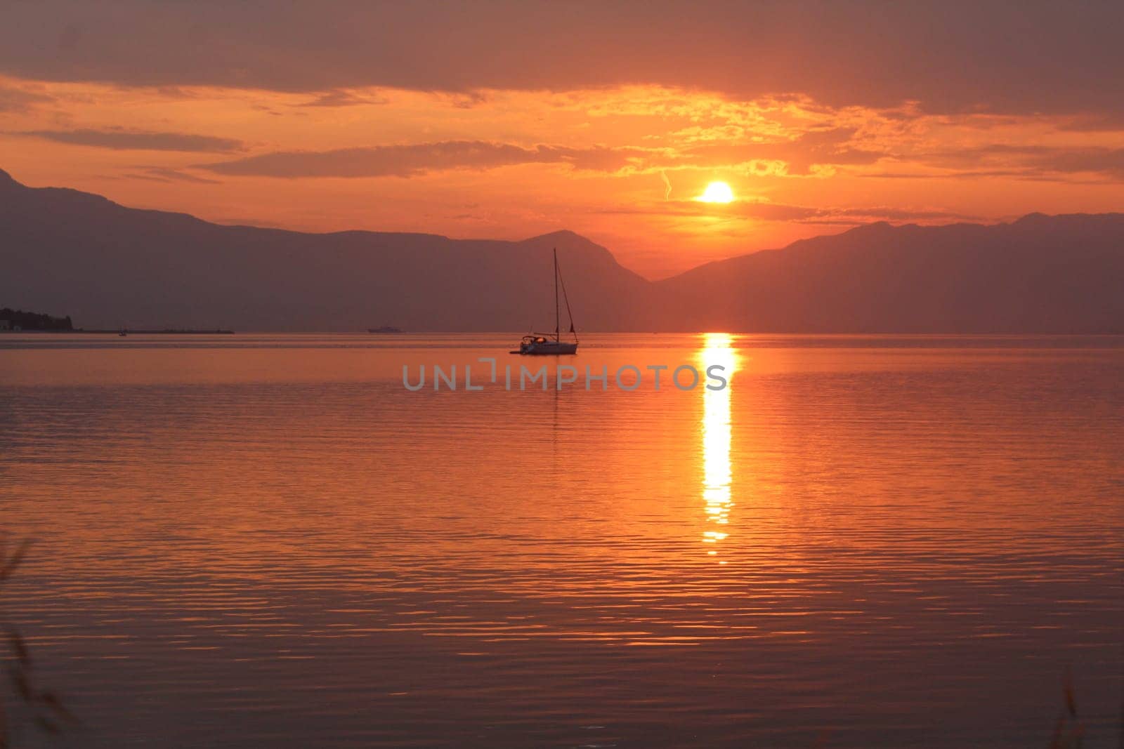 Scenic sunset and a lonely sailboat at the coast of Trogir, Croatia