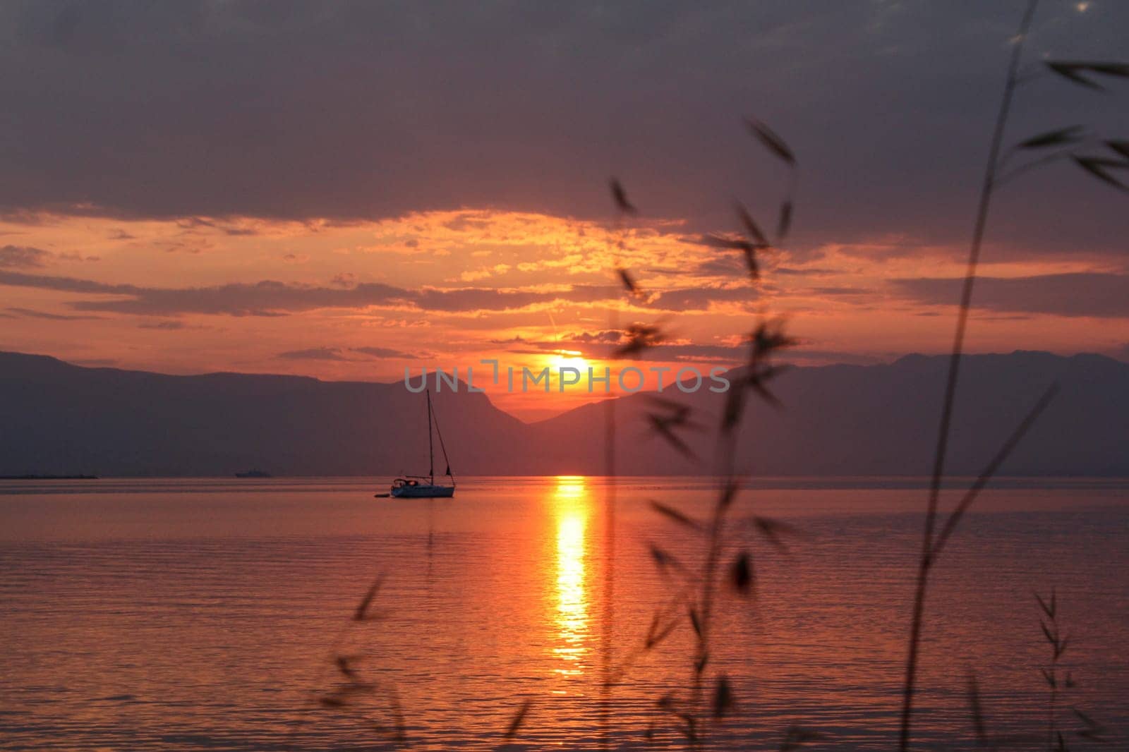 Scenic sunset and a lonely sailboat at the coast of Trogir, Croatia