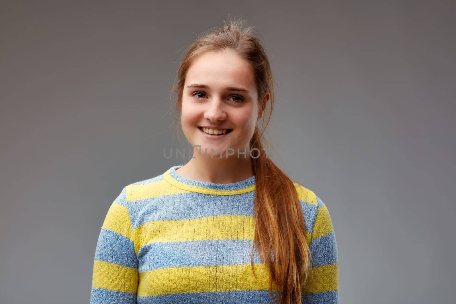 young beautiful woman in yellow striped sweater smiles pretty moderately