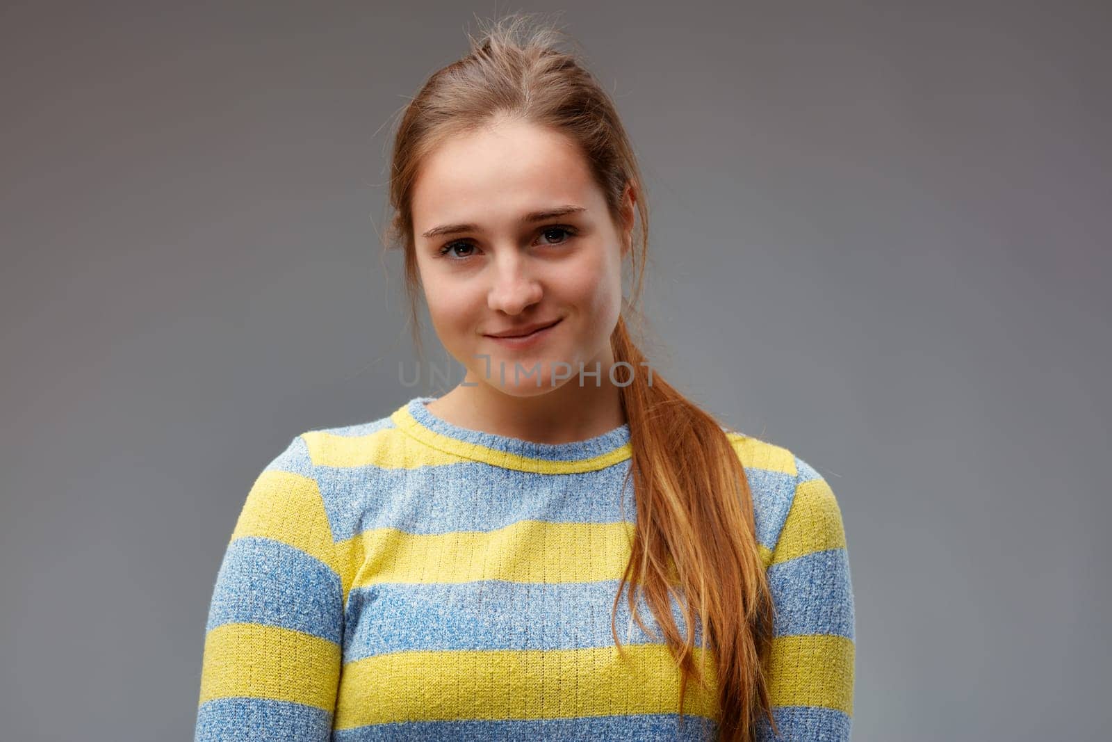 young woman with a restrained smile, waiting for the revelation of a secret or a nice surprise
