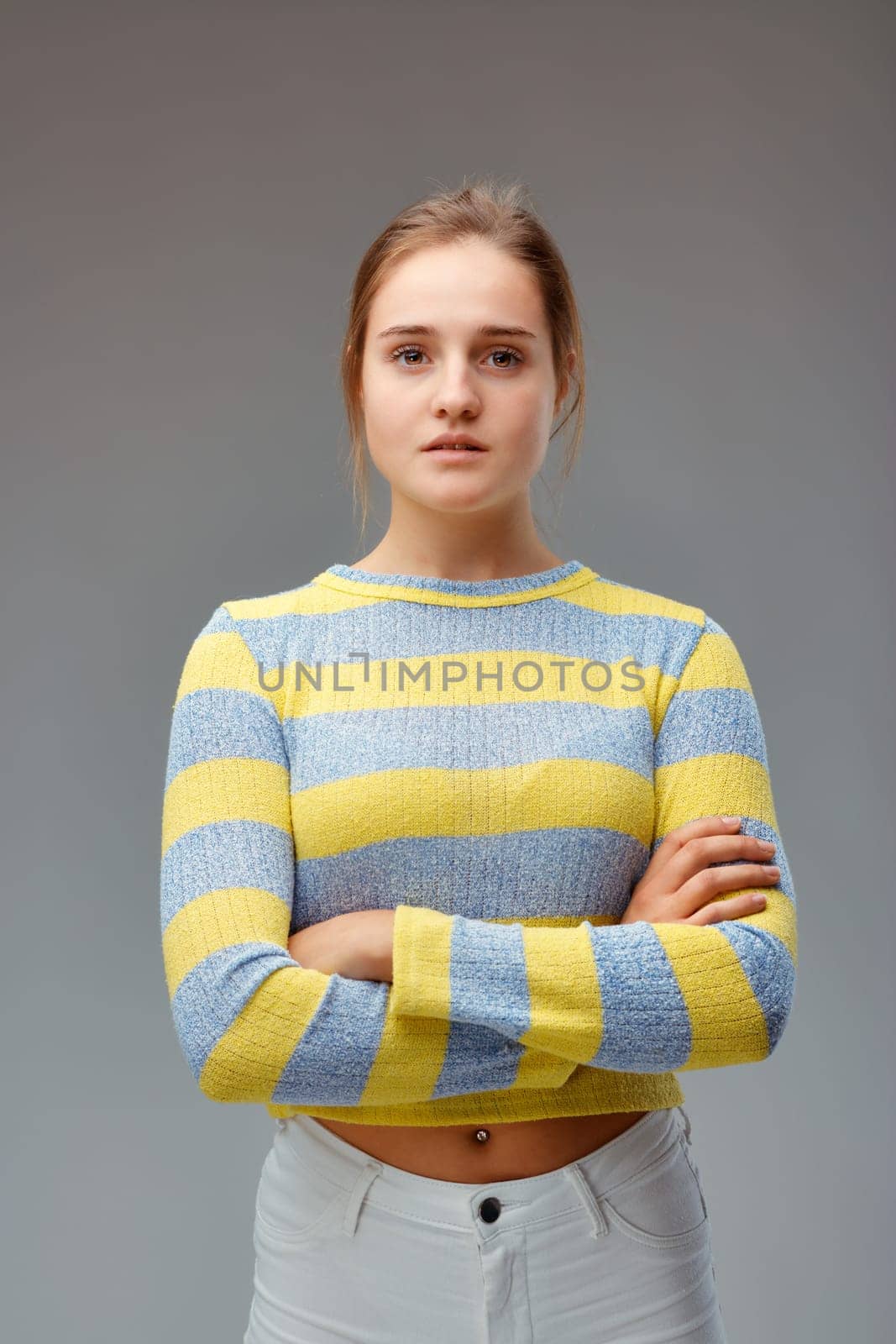 Strong and beautiful. Portrait of a young woman with a yellow striped sweater, her arms folded and a proud and determined look.