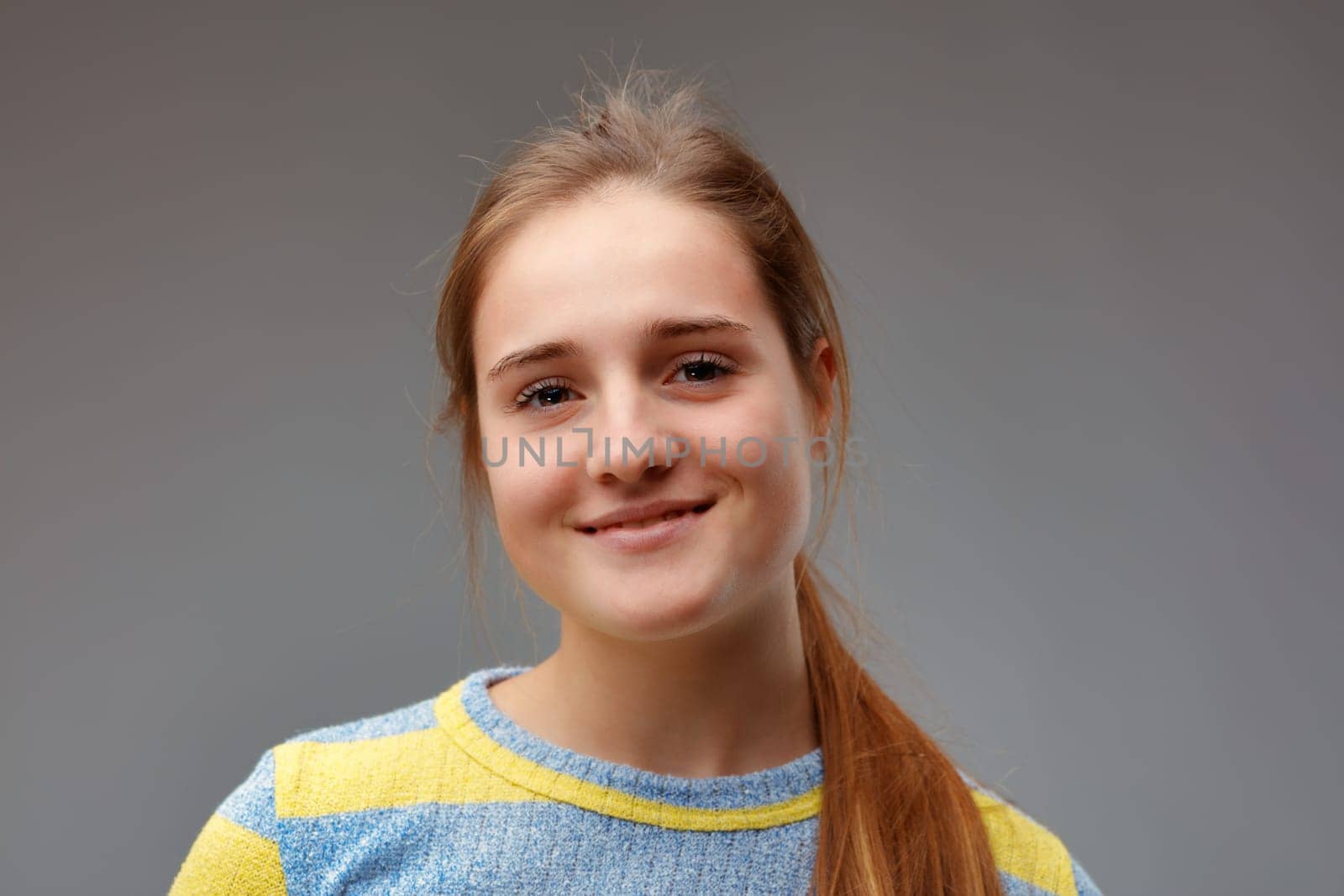 young beautiful woman in yellow striped sweater smiles adorably because she is satisfied