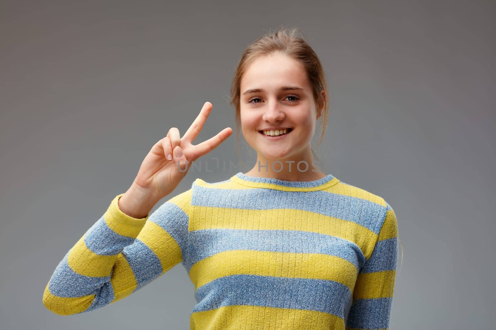 I won! portrait of smiling young woman making victory gesture with hands