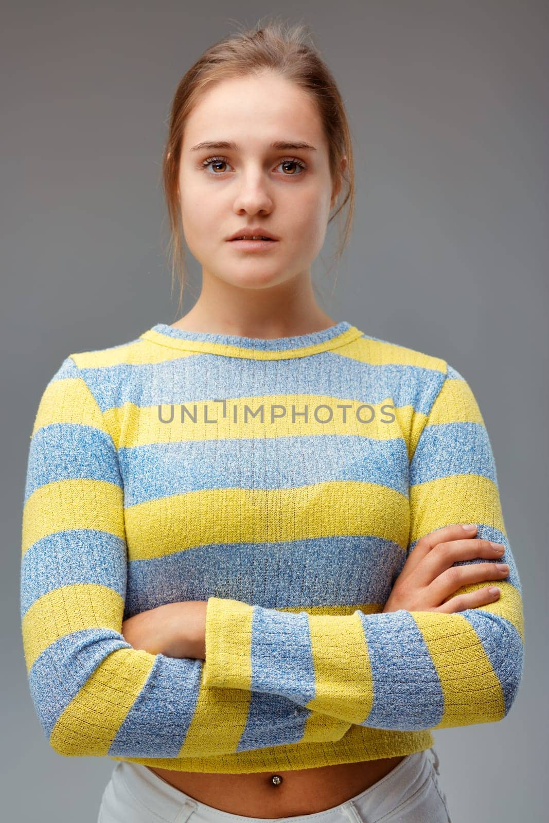 Strong and beautiful. Portrait of a young woman with a yellow striped sweater, her arms folded and a proud and determined look.