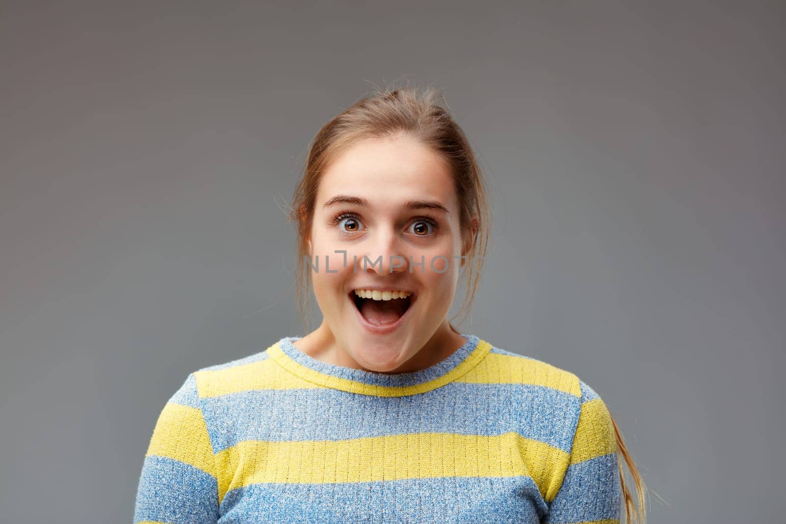 joyful surprise, portrait of a young woman positively surprised and almost astonished, with open mouth and perfect teeth