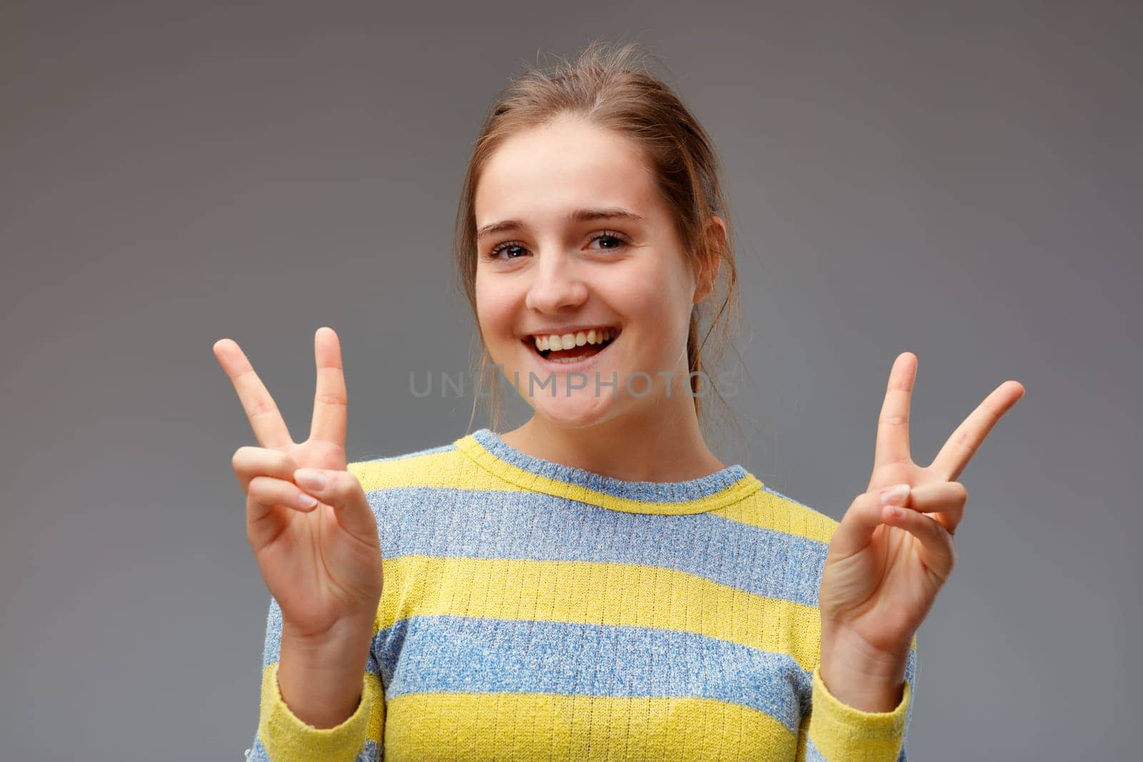 I double won! portrait of smiling young woman making victory gesture with the two hands