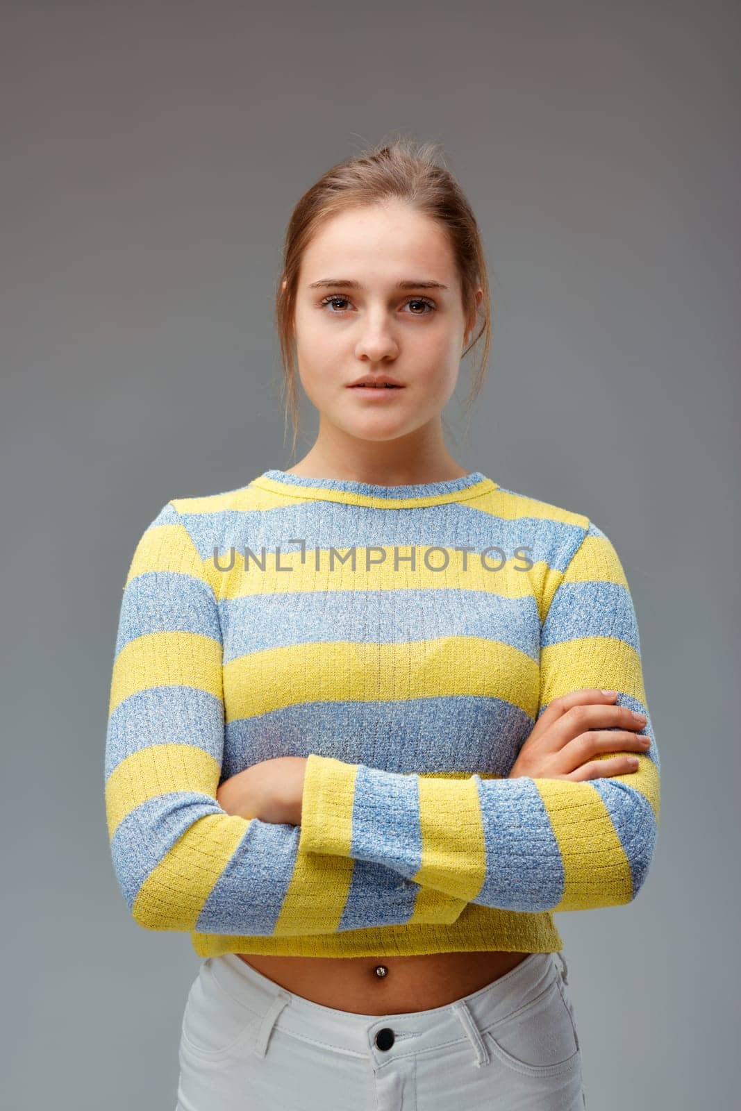 Strong and beautiful. Portrait of a young woman with a yellow striped sweater, her arms folded and a proud and determined look.
