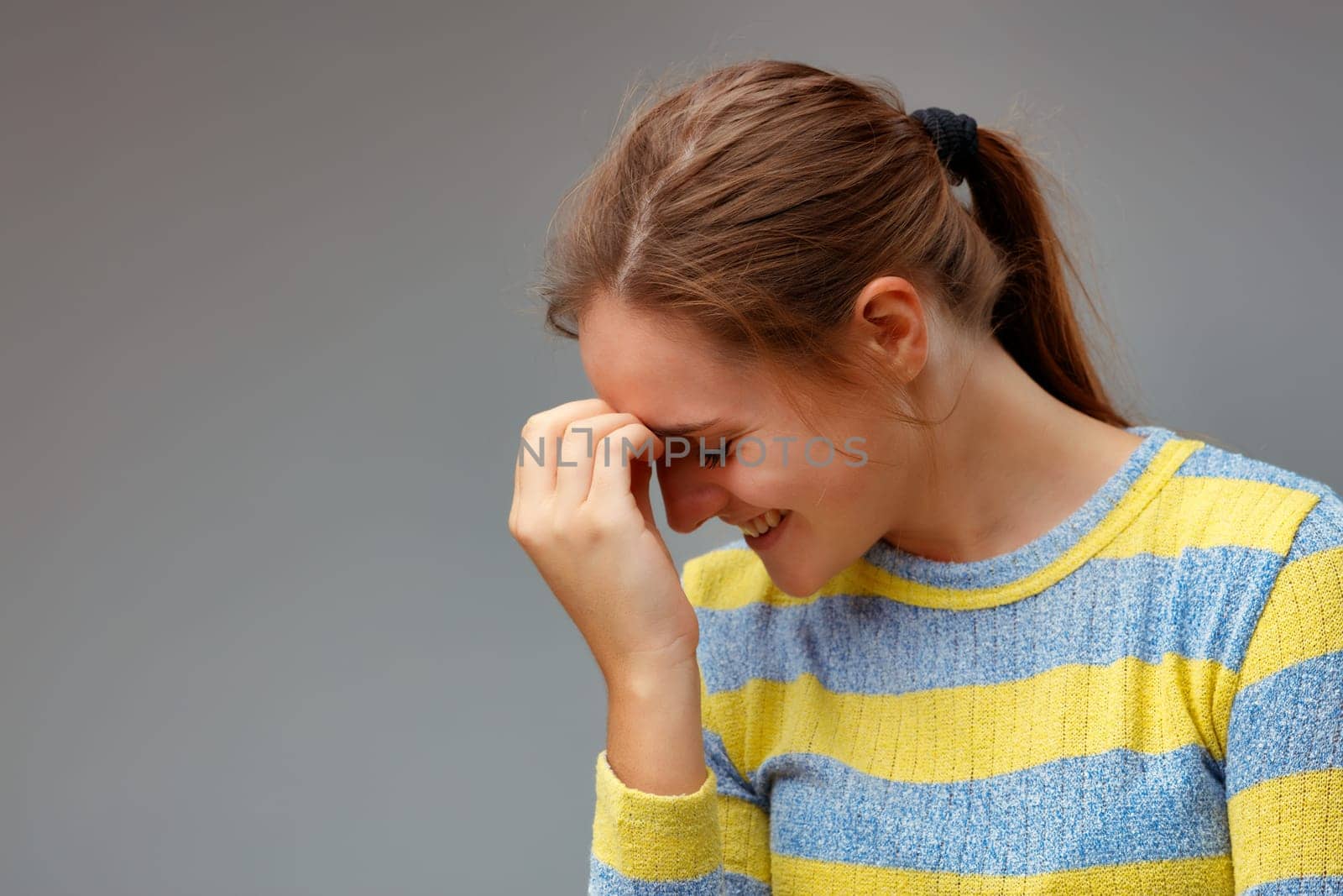 how did I not think about it before? Portrait of a young woman smiling with her eyes closed, placing her hand on her forehead.