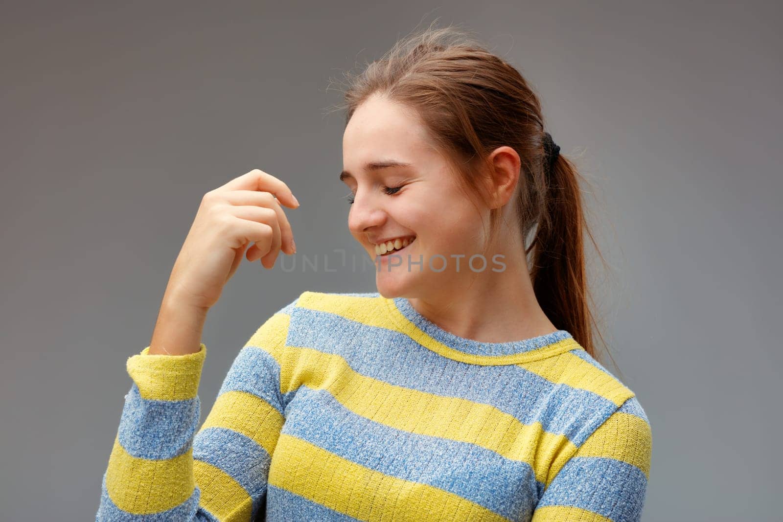 Young woman caught in the act of letting go of laughter, she is so natural and relaxed, with one hand in a natural position without any particular purpose.