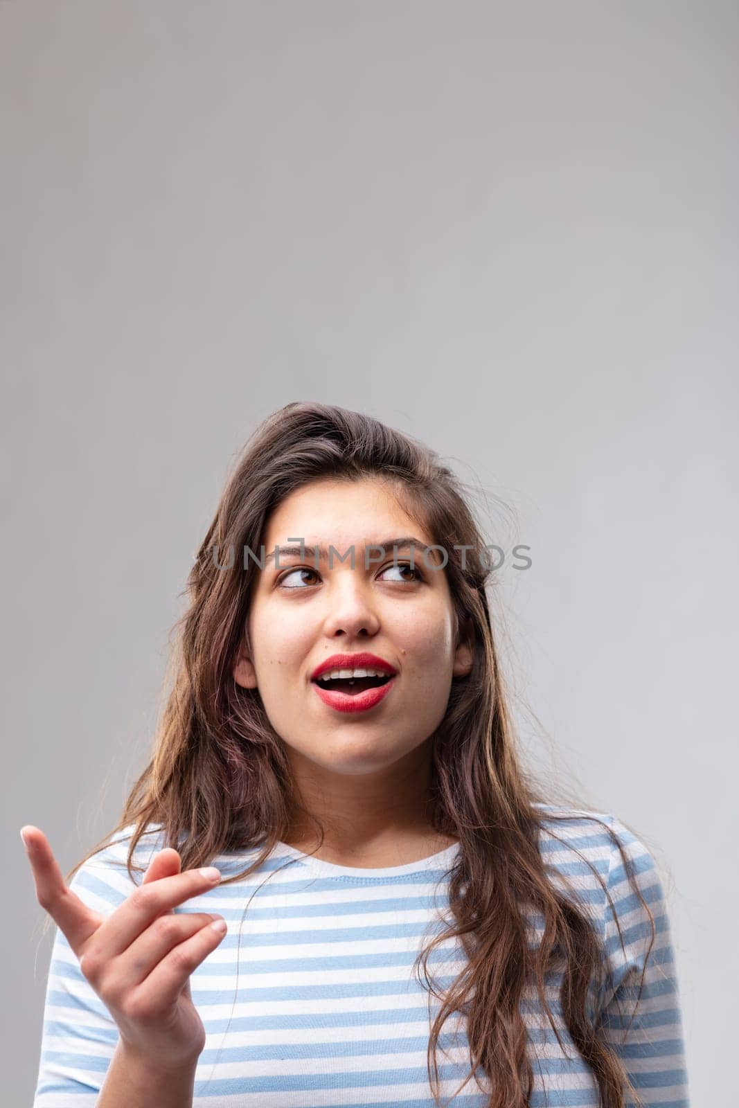 Young woman having a eureka moment of inspiration as she suddenly has a bright idea or finds the solution to a problem over a grey studio background