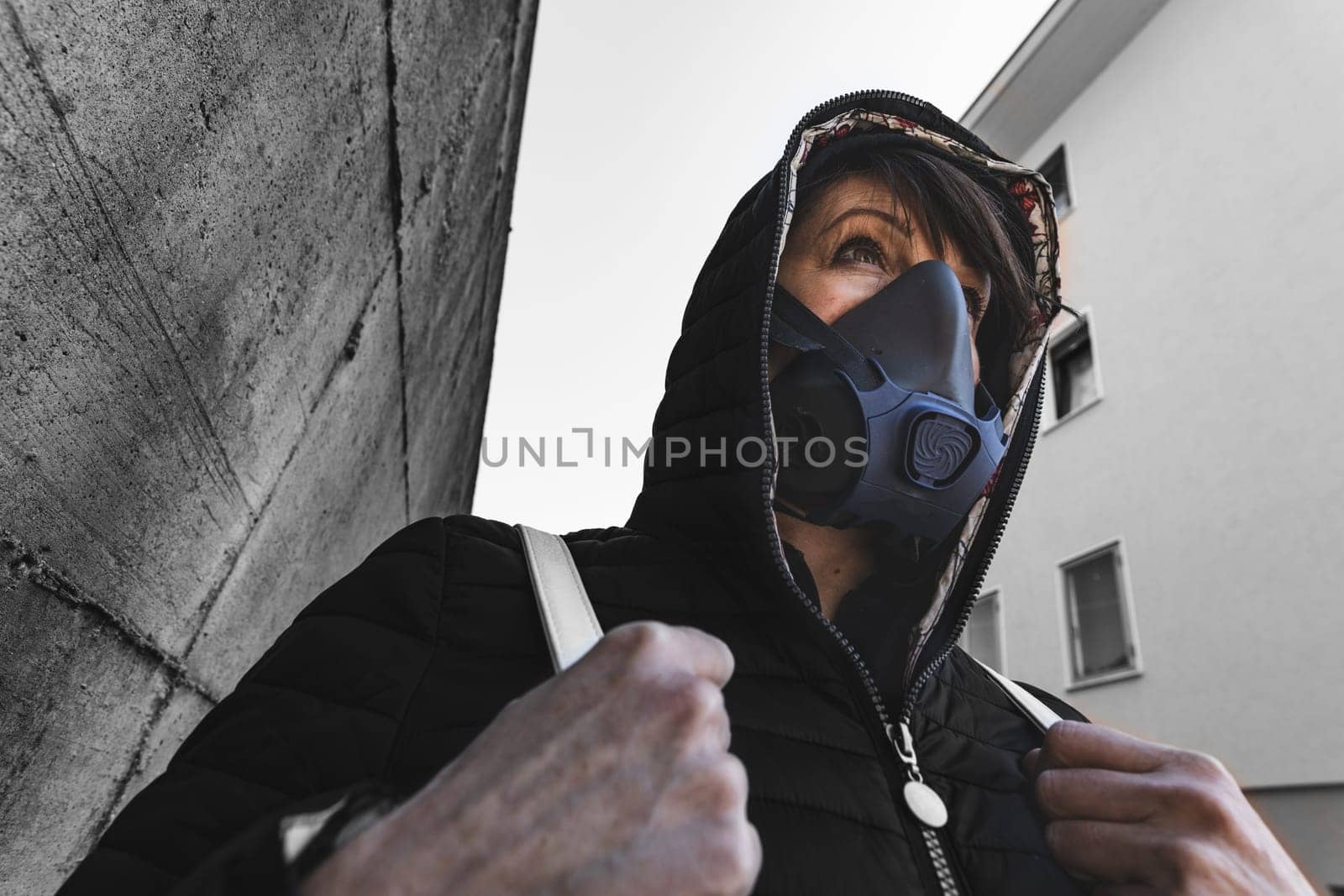 woman with a gas mask walking on the city streets surviving a corona virus pandemic or post atomic world