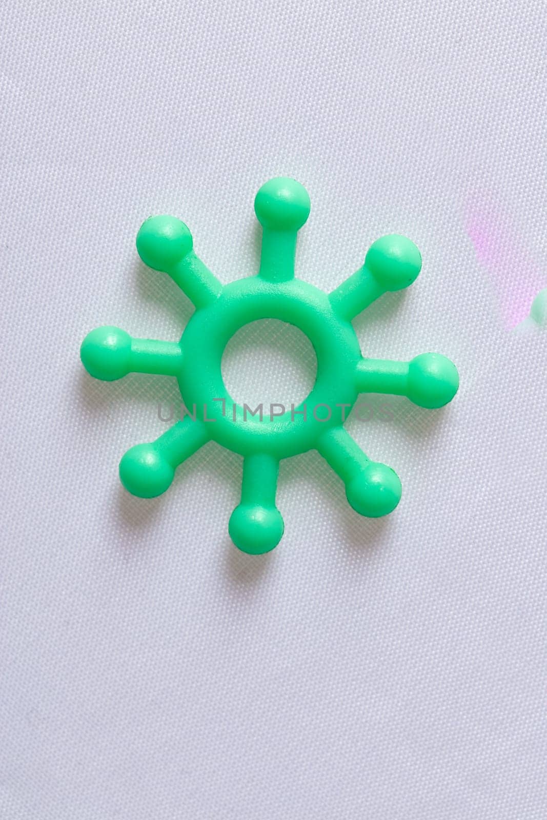 Single green plastic Covid-19 molecule model on a white background with copy space for use in coronavirus themed concepts