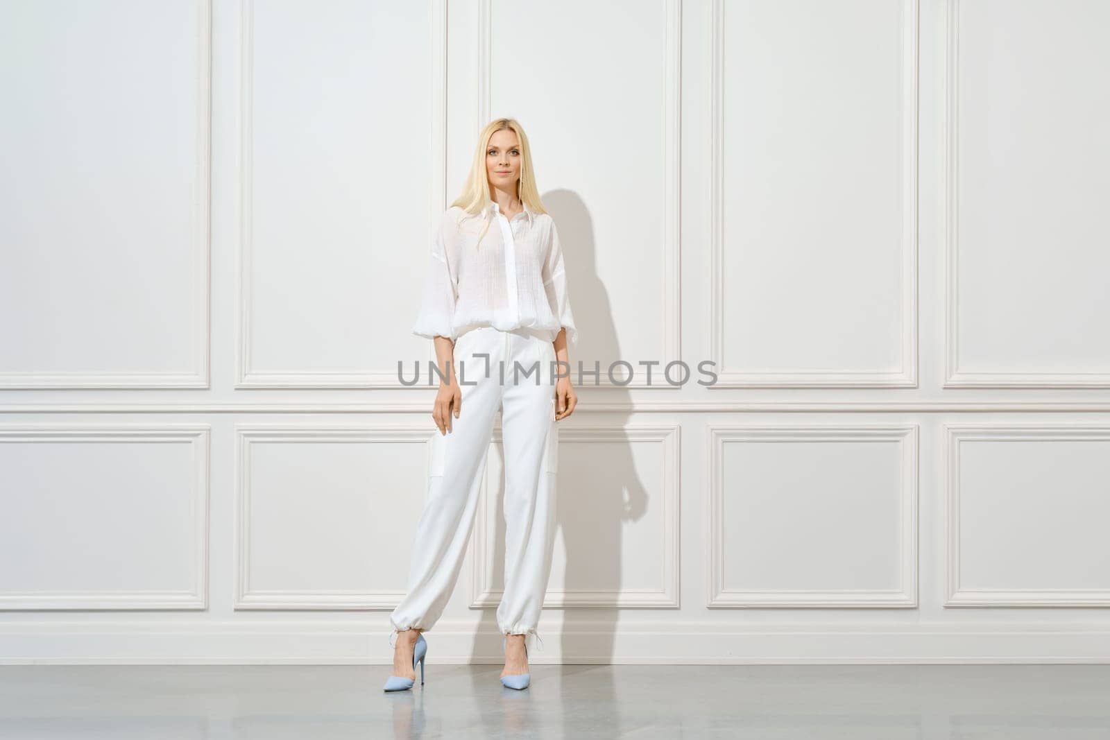 Confident blonde woman in total white outfit