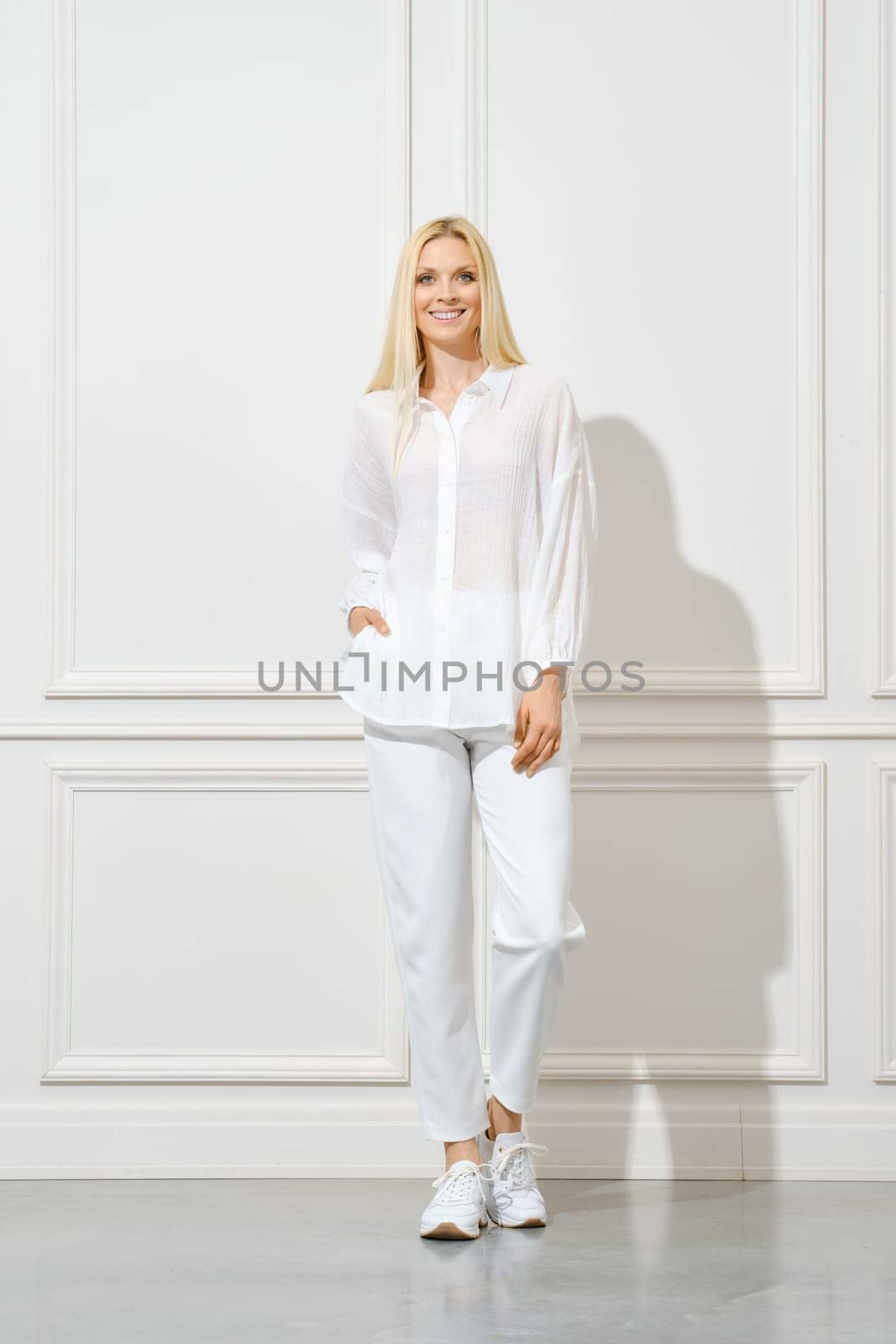 Smiling woman in white cotton shirt and trousers with pockets posing