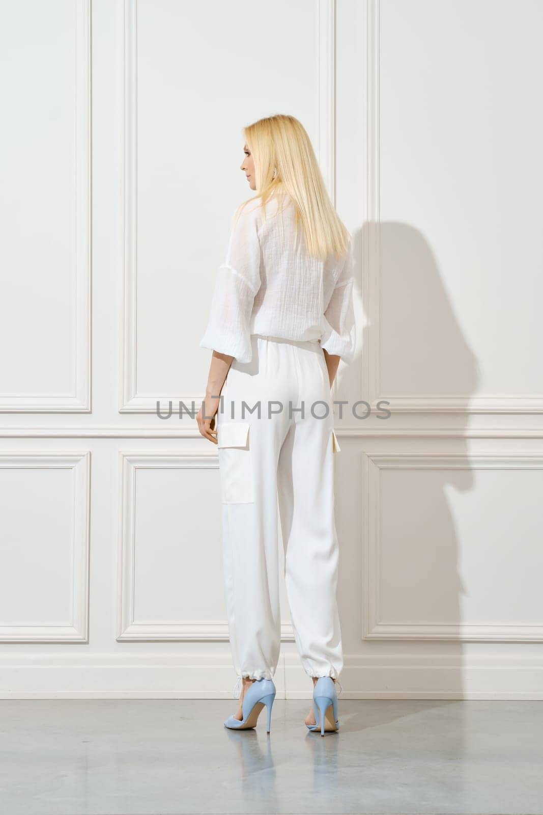 Back view of a woman in white cotton shirt and trousers