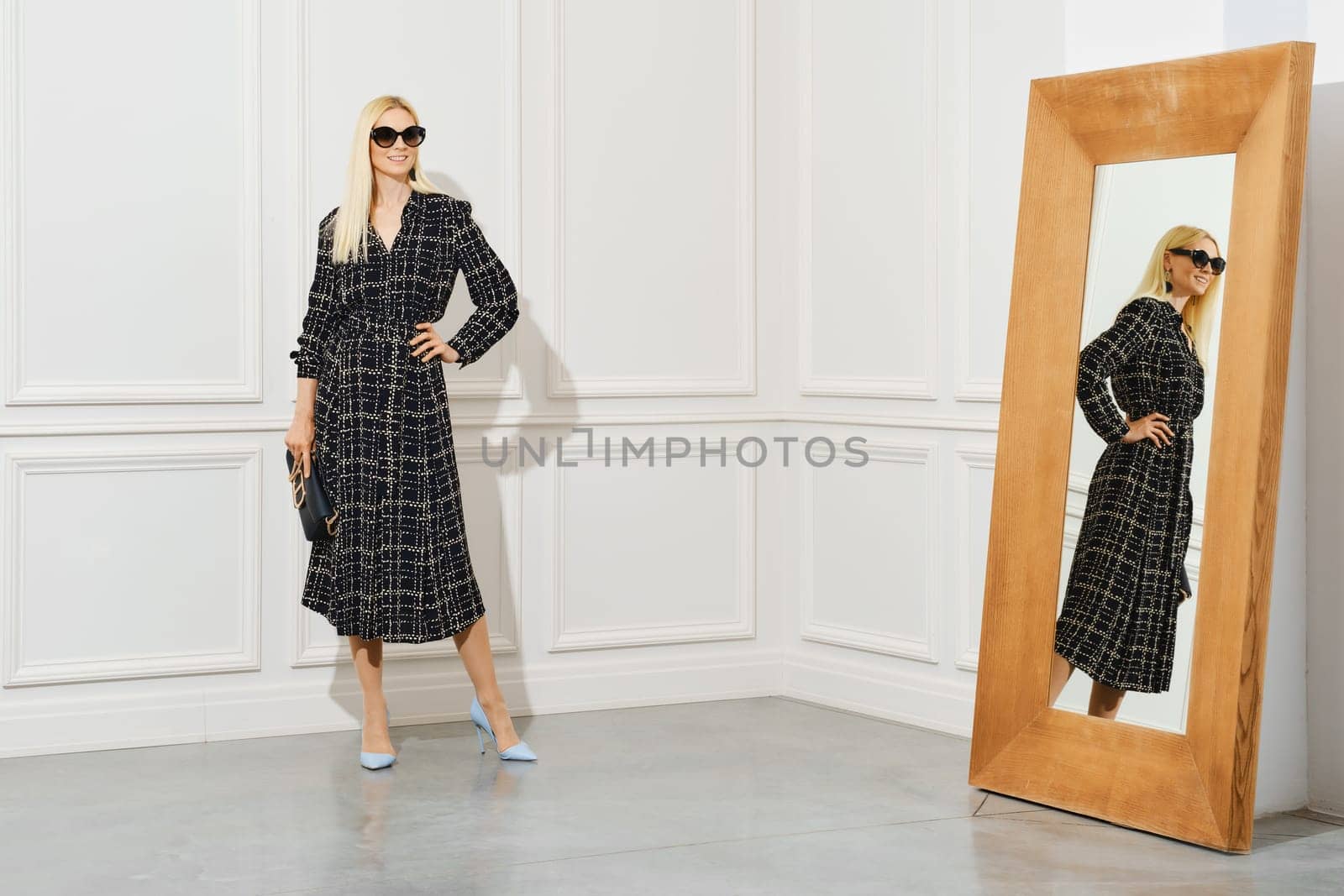 Portrait of smiling woman in long wool dress by thelarge mirror
