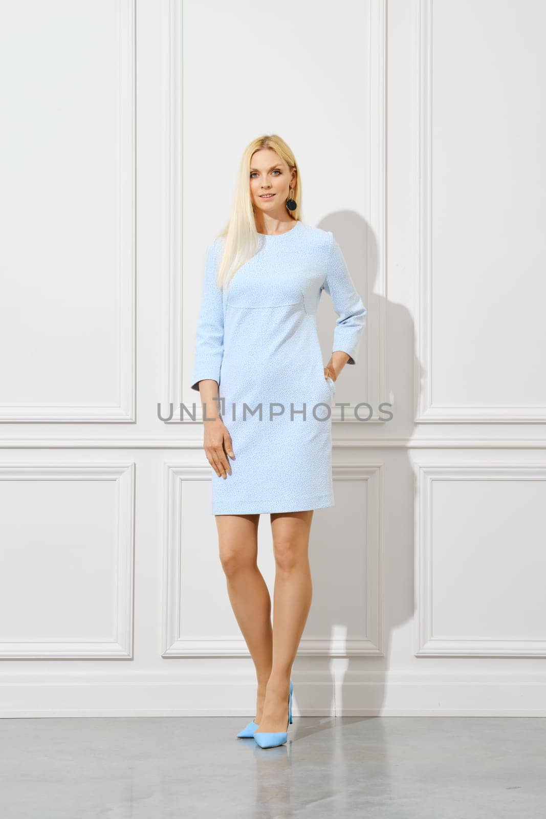Cute blonde woman in pale blue dress welcomes spring