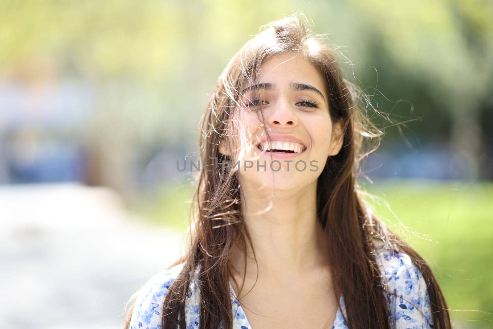 Front view portrait of a happy woman laughing with tousled hair a windy day