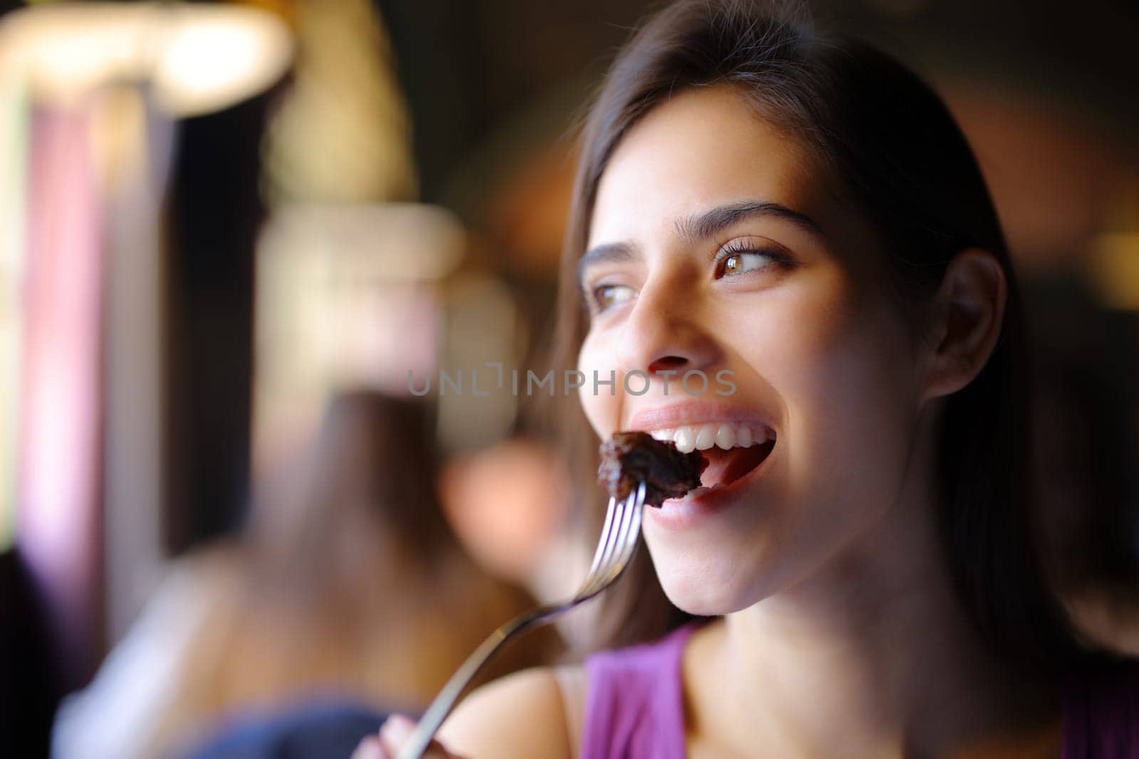 Happy woman eating meat using fork in a restaurant