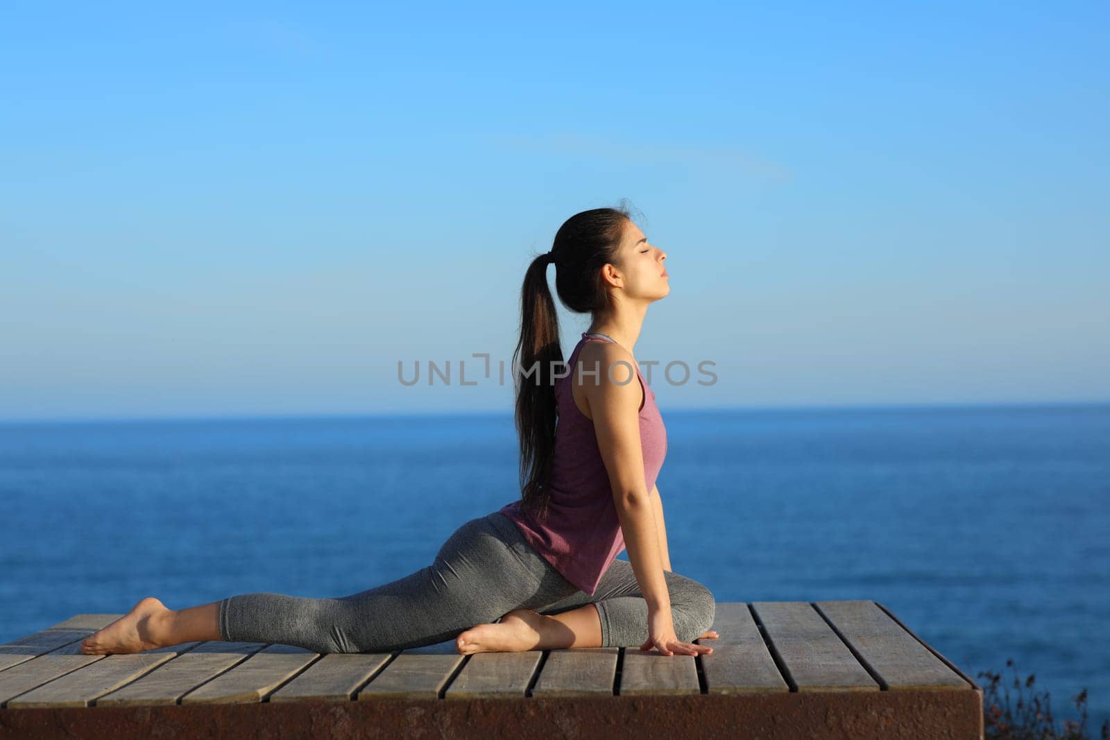 Profile of a woman doing yoga exercises on the beach