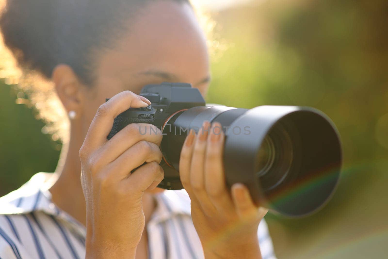 Black photographer taking pictures with mirrorless camera in a park