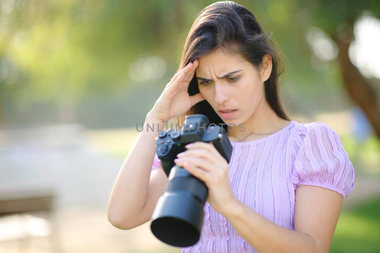Worried photographer checking result on camera in a park