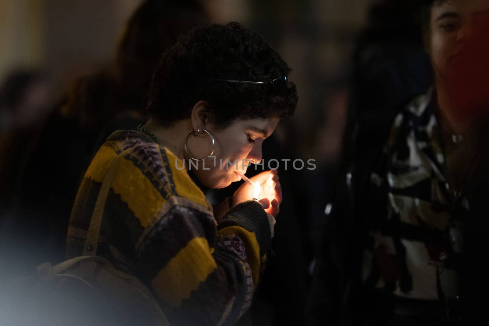PORTUGAL, LISBON 11-25-2022: the March for the End of Violence Against Women - a woman lighting the cigarette in the crowd. Mid shot