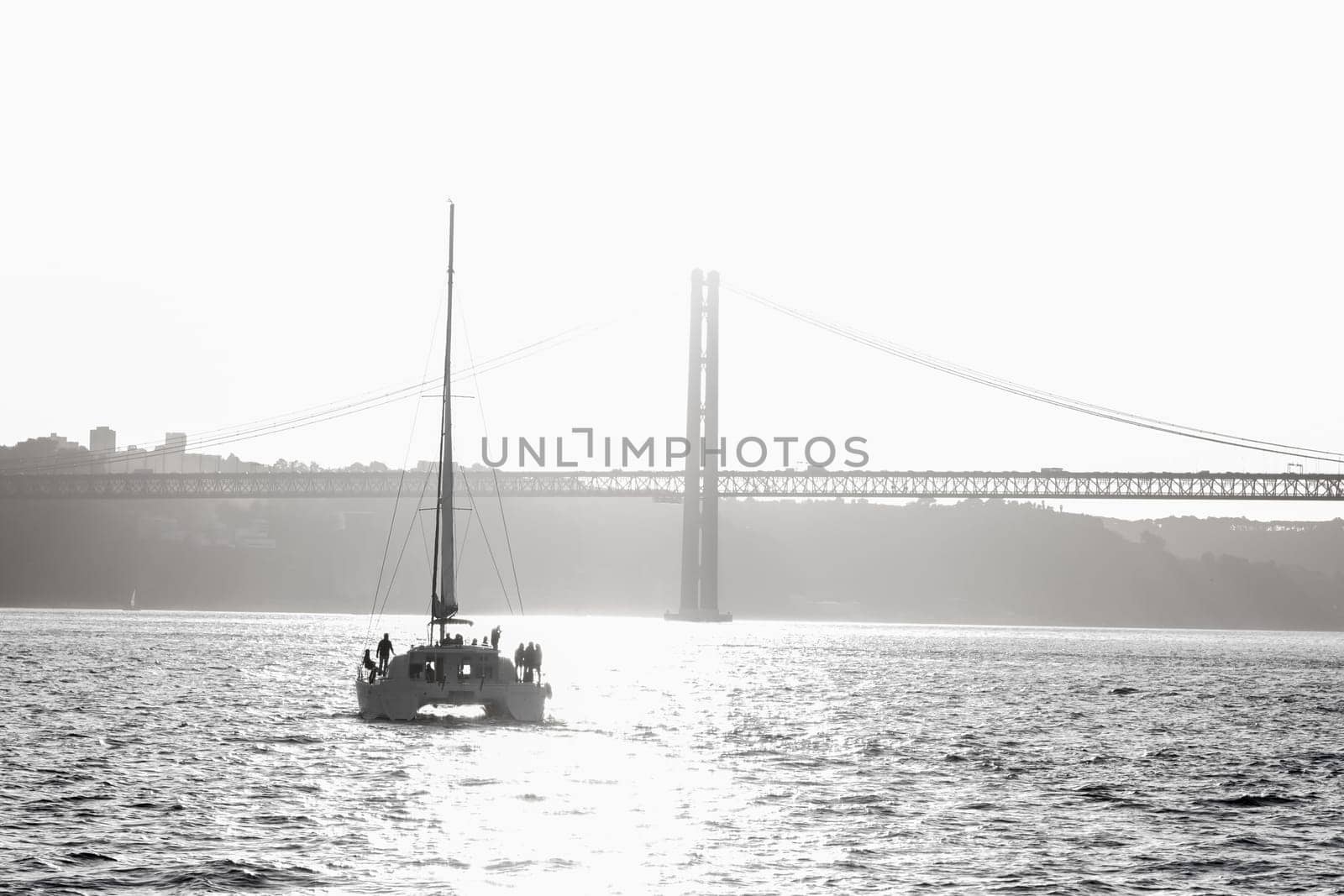 People standing on a sailing yacht sailing along the river towards the bridge. Mid shot