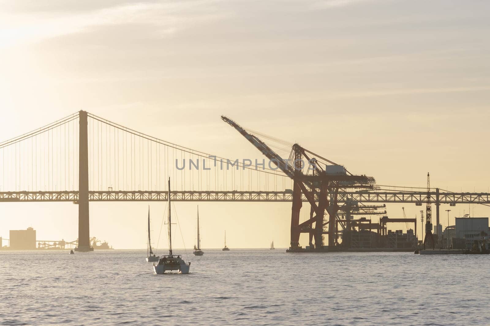 Sailboat sails down the river at industrial cranes. Mid shot