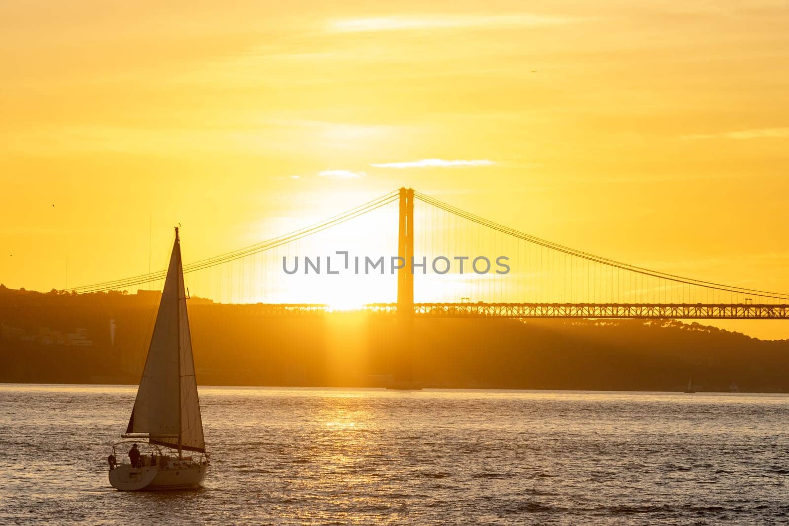 Sailing boat floating on the river at an orange sunset. Mid shot