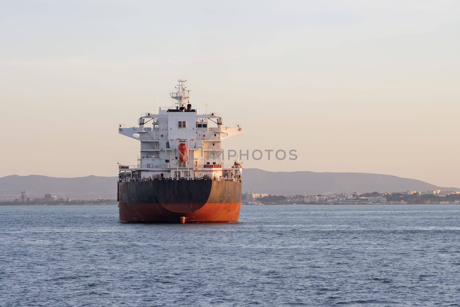 An industrial transport vessel sails on a river. Mid shot