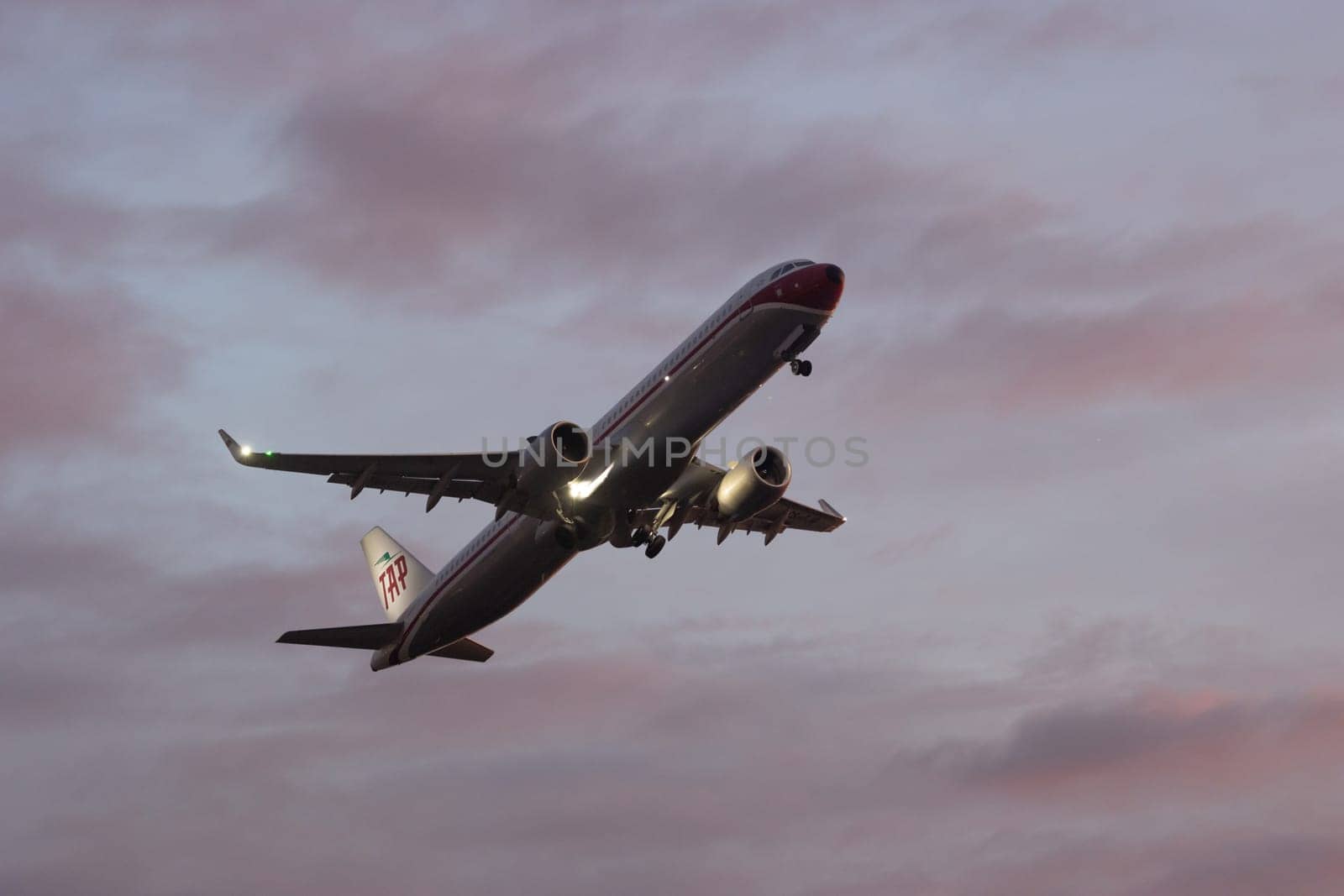 30 November 2022 PORTUGAL, LISBON: a large plane gains altitude in a purple sky. Mid shot