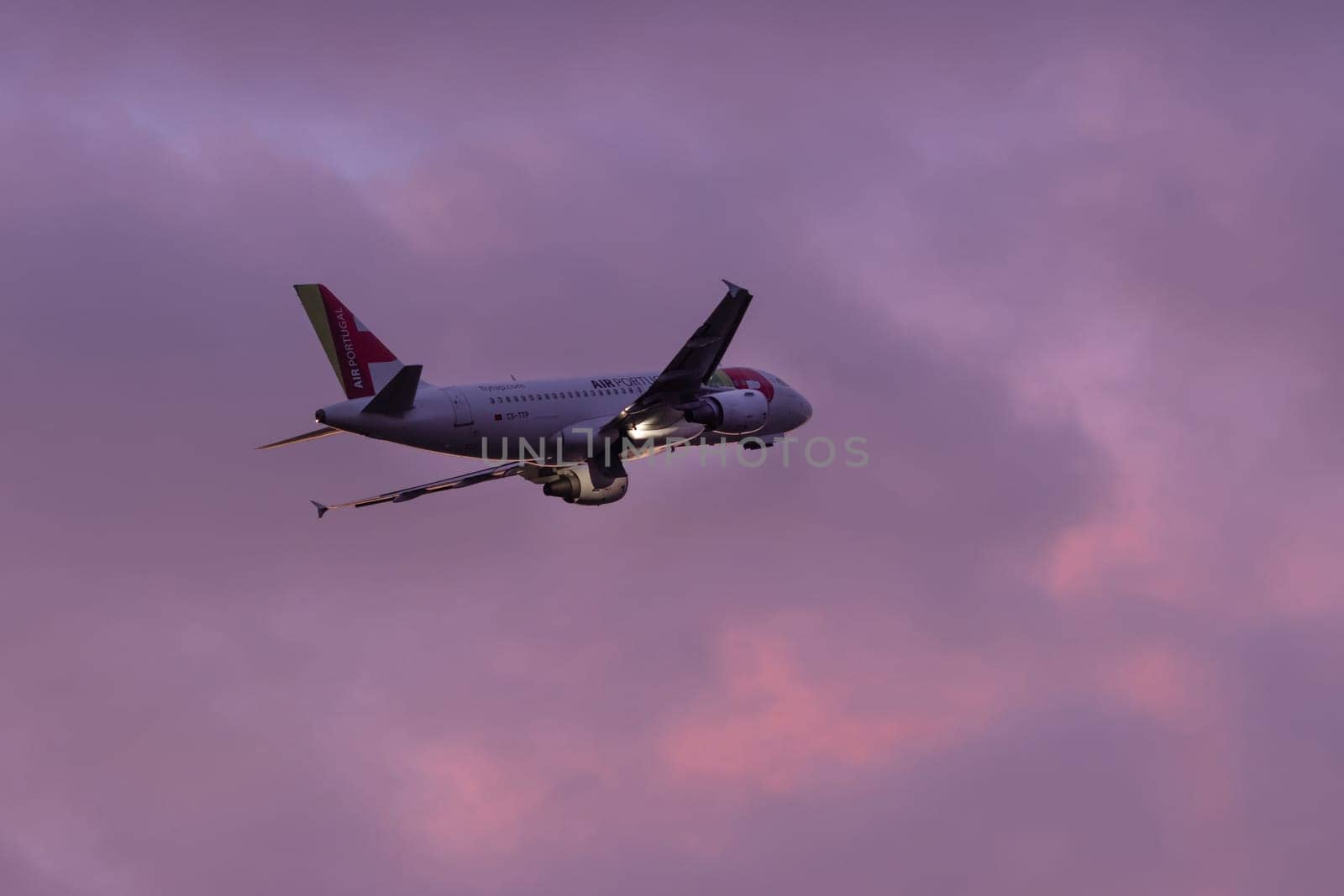 30 November 2022 PORTUGAL, LISBON: an AIRPORTUGAL airplane flies in the sky at purple sunset. Mid shot