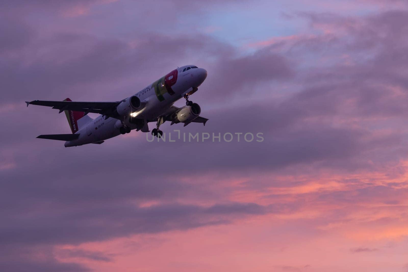 30 November 2022 PORTUGAL, LISBON: an airplane flies in the sky at purple sunset. Mid shot