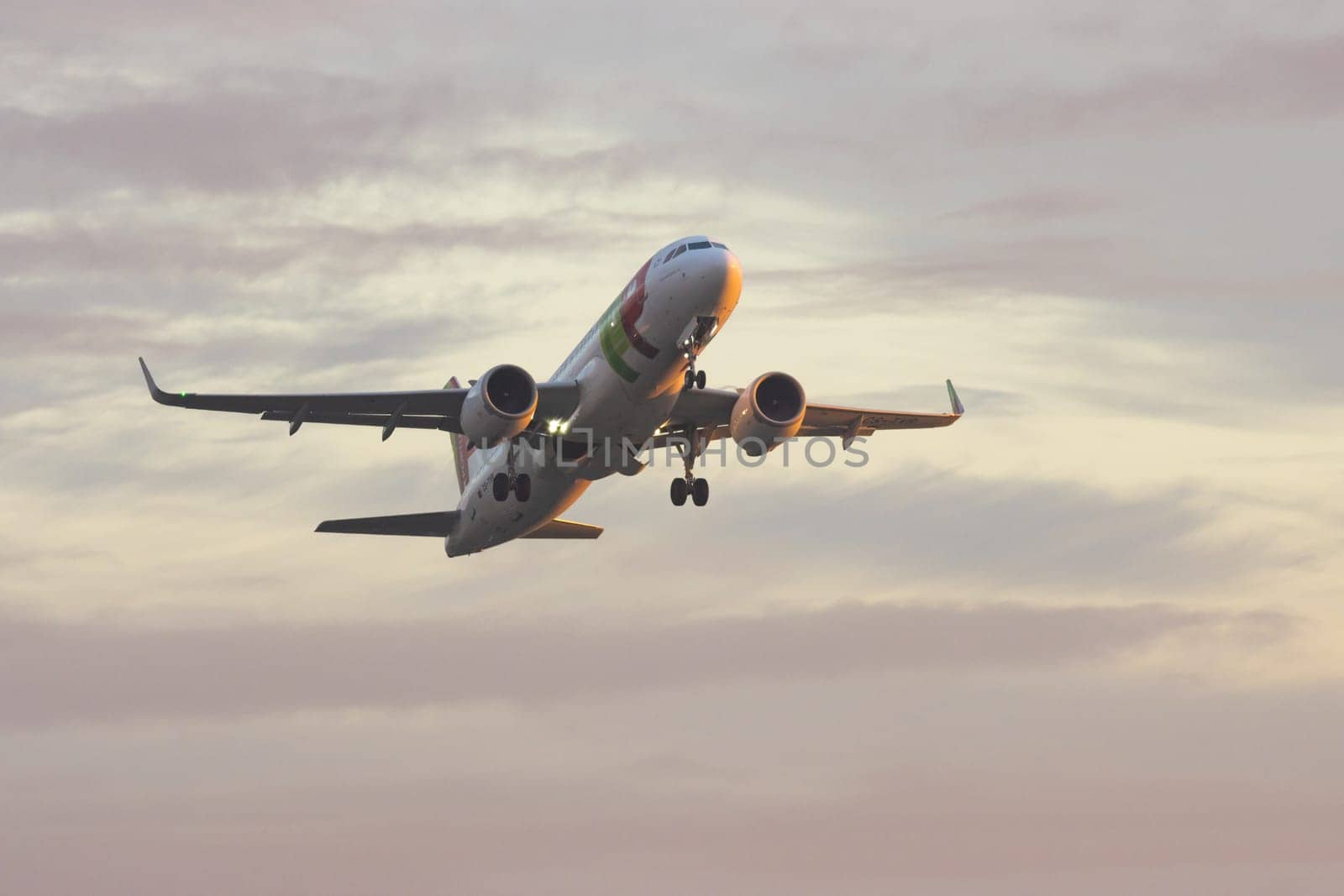 30 November 2022 PORTUGAL, LISBON: an AIRPORTUGAL airplane gains altitude in a purple sky. Mid shot