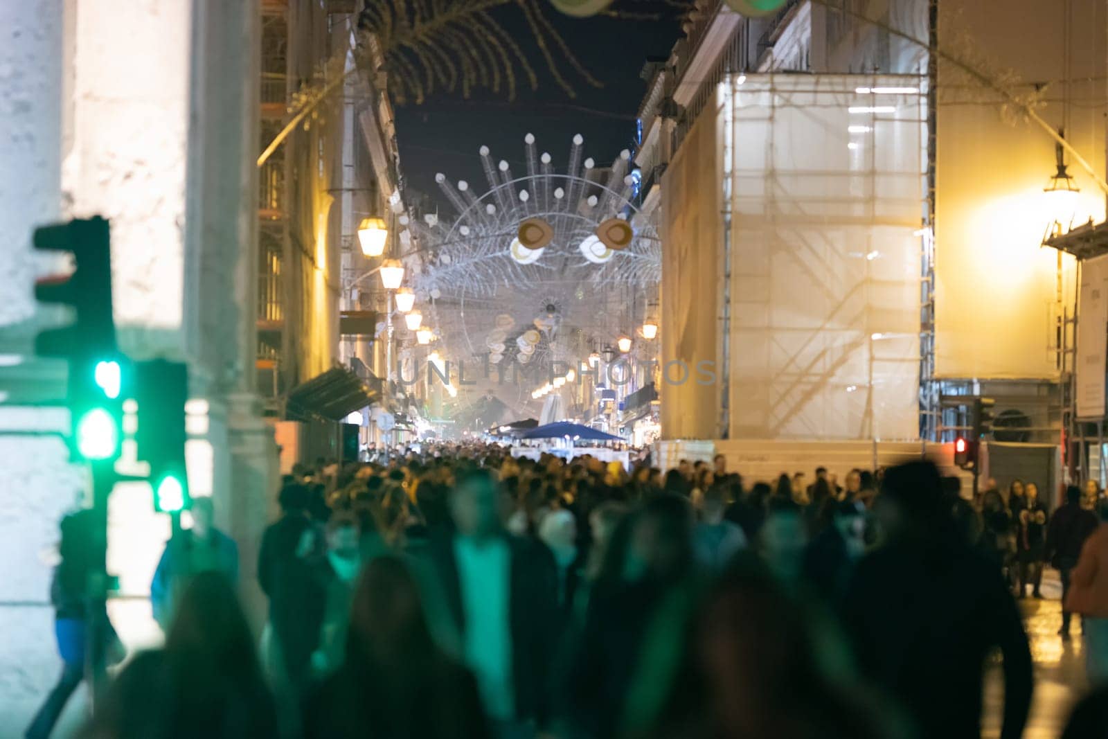People crowd on a European street decorated for Christmas. Mid shot