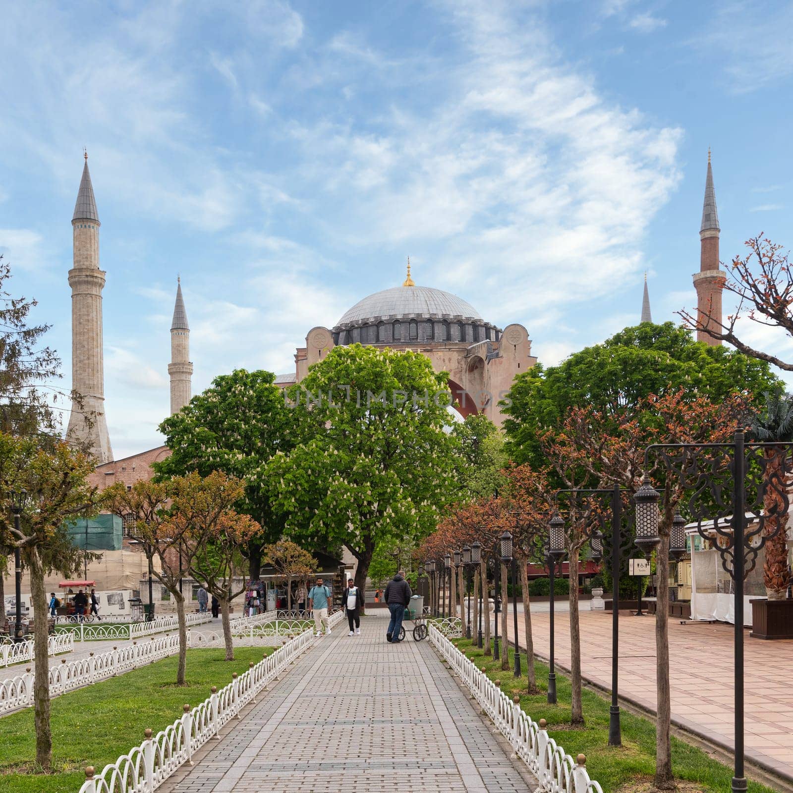 Istanbul, Turkey - May 11, 2023: Group of people walking down a sidewalk in front of the Hagia Sophia, a UNESCO World Heritage Site. The Hagia Sophia is a former church, museum, and now mosque