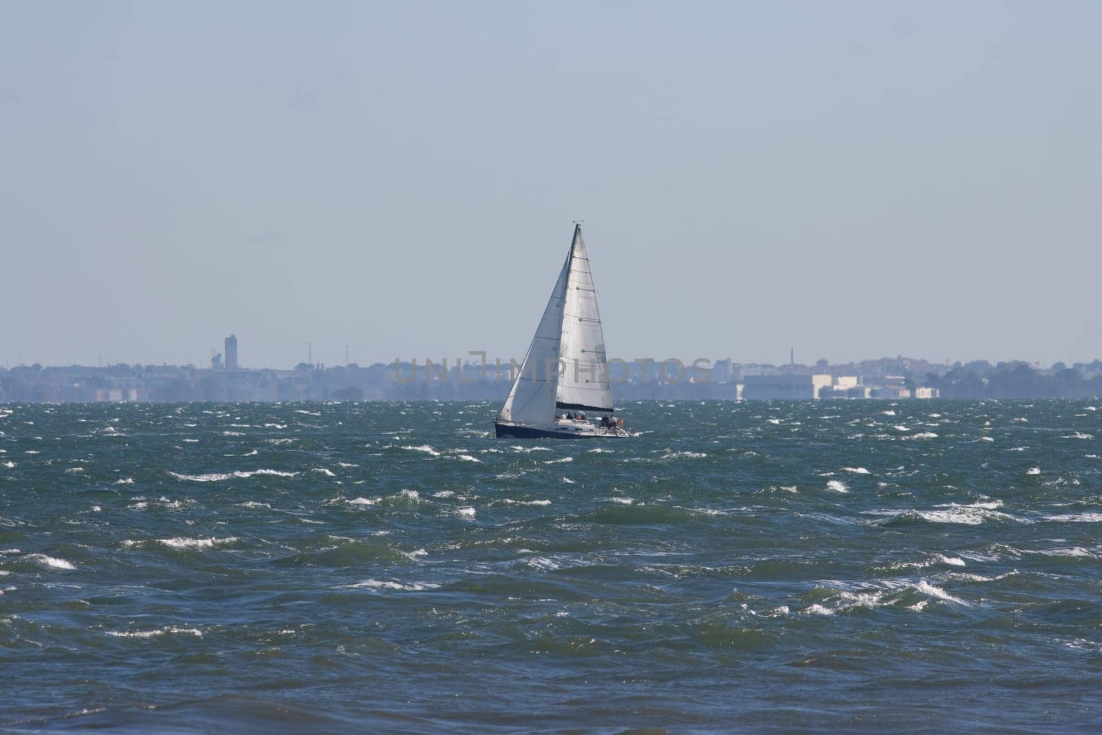 Sailboat sails the blue sea at grey weather. Mid shot